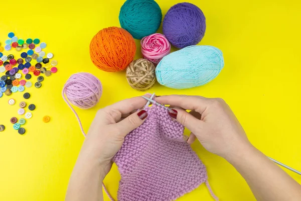 Das Mädchen strickt einen Kinderschal auf gelbem Hintergrund — Stockfoto