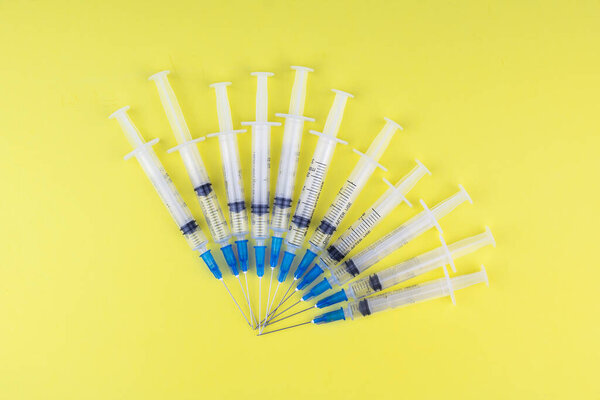 a lot of syringes lying next to each other on a yellow background. Vaccination, doping, drugs