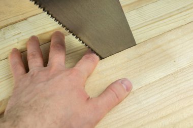 Adamın eli, güvenlik kurallarına uymayan bir el testeresinin altında kaldı.