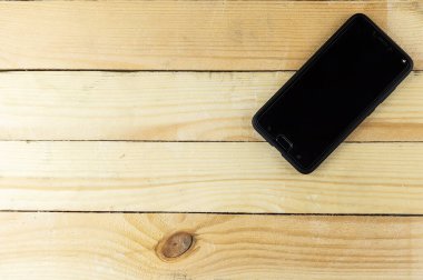 Akıllı telefon ahşap bir yüzeyde yatıyor. Yüksek teknoloji ve ağacın yapısı.