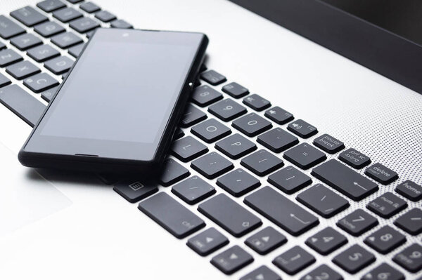 ноутбук в открытом формате, со смартфоном на клавиатуре
.