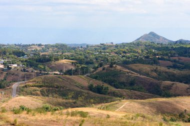 Dağları ve mavi arkaplanı olan bir tepedeki şehir manzarası.