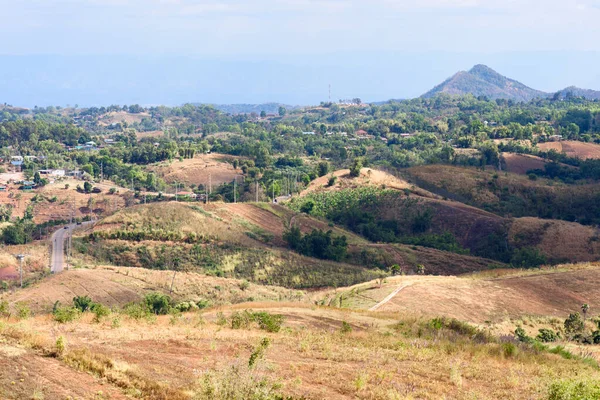 Dağları ve mavi arkaplanı olan bir tepedeki şehir manzarası.