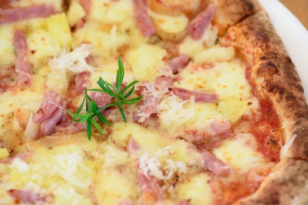 Beyaz tabakta ananas, jambon ve parmesan peynirli ev yapımı Hawaii pizzası.