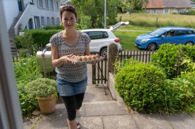 Evin kapısına gülümseyen genç bir kadın tarafından taze yumurta bırakılmış..