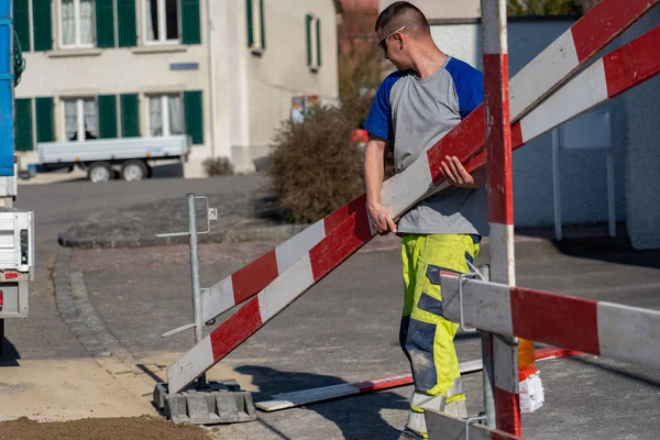 Trabajador de la construcción con ropa de advertencia está sosteniendo barreras de una construcción en sus manos . — Foto de Stock