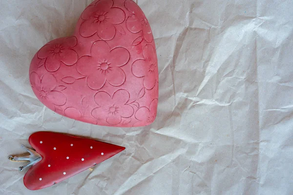 Valentýn, malé jahodové srdíčko s růžovým květovaným srdcem na bílém balicím papíru. — Stock fotografie
