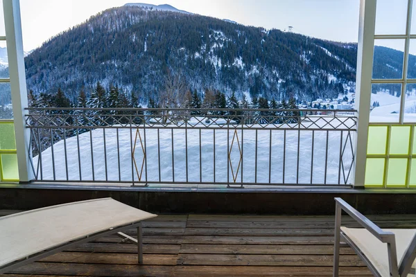 Relaxing chair on a balcony with view over mountain range of Davos on swiss mountain at winter day. — Stock Photo, Image