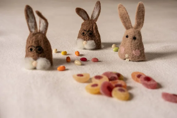 Three bunnies sitting between candys. — Stockfoto