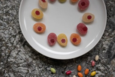Sweeties for easter. Easter candies in a raw in a white plate on a gray granite table.