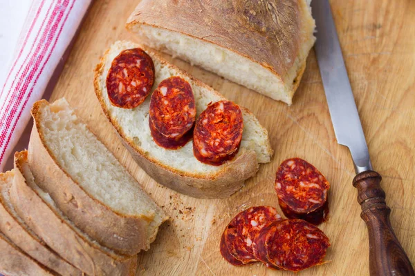 Coltello, pane fresco e salsiccia in tavola — Foto Stock