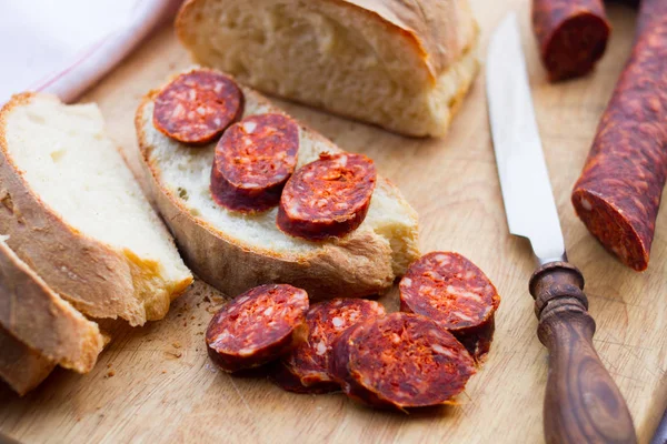 Нож, свежий хлеб и колбаса на столе — стоковое фото