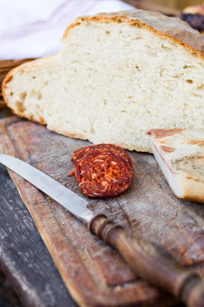 Coltello, pane fresco e salsiccia in tavola — Foto Stock