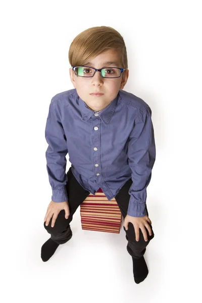 Boy sitting on a big pile of books — Stock Photo, Image