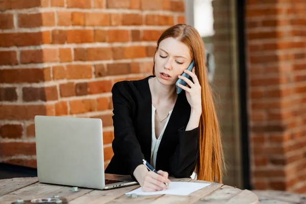 Redhead Chica Economista Sentado Oficina Ordenador Portátil Hablando Teléfono Inteligente — Foto de Stock