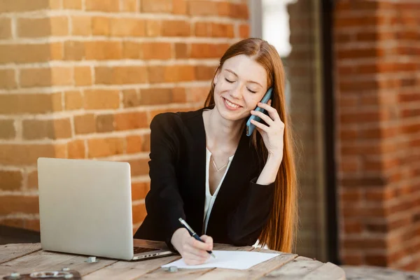 Economista Pelirroja Sentada Oficina Portátil Con Una Sonrisa Hablando Smartphone — Foto de Stock