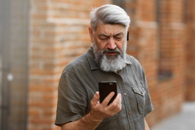 Gri saçlı bir adam bir iş adamı, online bir konferansta hoşnutsuzca konuşuyor.