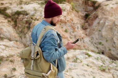 Haftasonu yürüyüş yaparken akıllı telefonuyla mesaj atan sakallı bir adam.