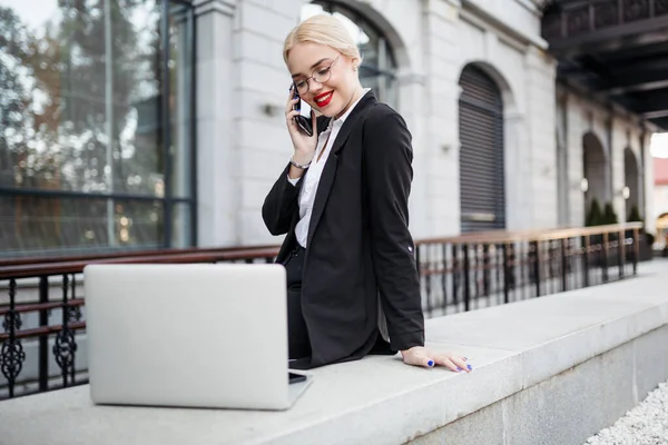 漂亮的女职员在商务旅行中 用智能手机打电话 站在酒店的门廊上 — 图库照片