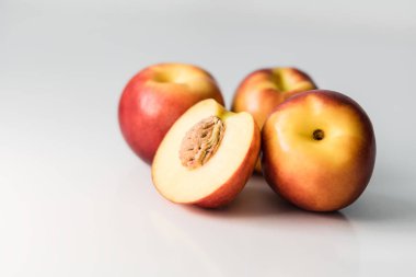 Olgun kırmızı, turuncu ve sarı nektarinler, şeftaliler, beyaz bir masada elmalar. Lezzetli parlak meyveler. Sağlıklı beslenme. Ayrı nesne.