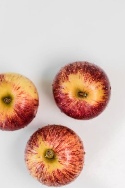 Beyaz parlak mutfak masasında su damlacıkları olan taze kırmızı çizgili elmalar. Lezzetli, sulu meyveler. Sağlıklı yeme izole nesne