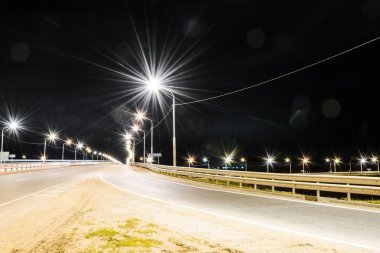 Gece karayolu parlak ışıklar ve ışık çizgileriyle aydınlanıyor. Egzoz boruları olan bir fabrika. Ay ve yıldızlar, bulanık bulutlar ve yemyeşil çimenler. Yazı: 