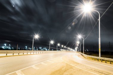 Gece karayolu parlak ışıklar ve ışık çizgileriyle aydınlanıyor. Egzoz boruları olan bir fabrika. Ay ve yıldızlar, bulanık bulutlar ve yemyeşil çimenler.