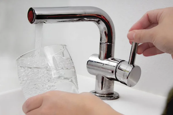 Vrouwelijk glas bij waterkraan en vullen van water met loodverontreiniging — Stockfoto