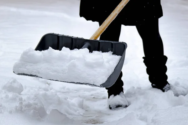 Female shovelling snow with a shovel full of snow, during winter. — ストック写真