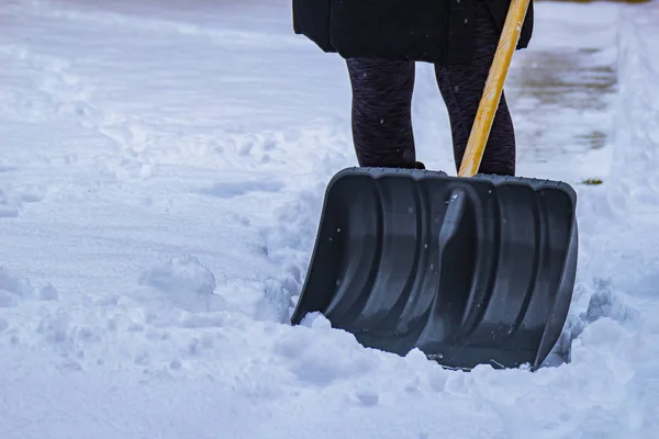 Female shovelling snow with an empty shovel, during winter. — ストック写真