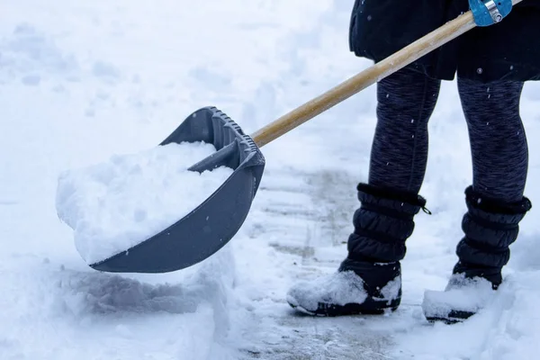 Жіночий лопата сніг з повним сніговим лопатою на боці, взимку . — стокове фото