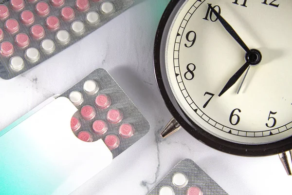 Таблетки контролю народжуваності з годинником і мармуровим фоном — стокове фото