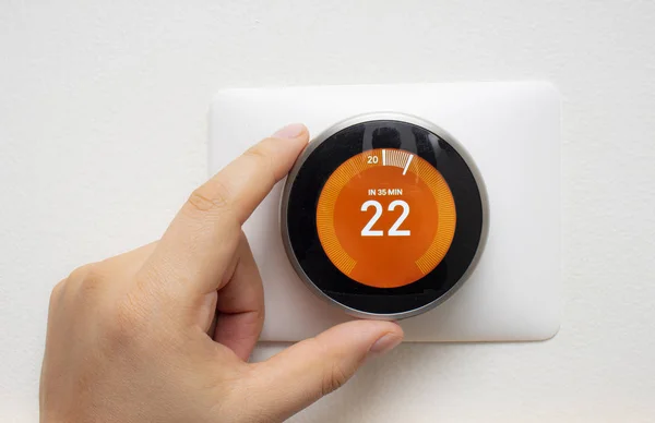 Smart termostat med en person som värmer upp rumstemperaturen med en mjuk skugga — Stockfoto