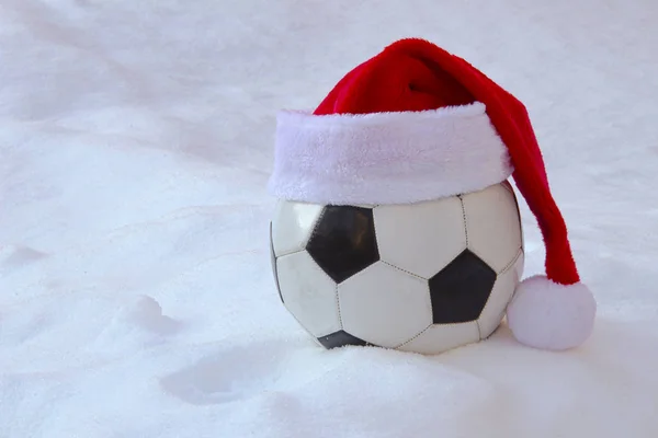 Voetbal met een Kerstmuts op sneeuw voor Kerstmis — Stockfoto