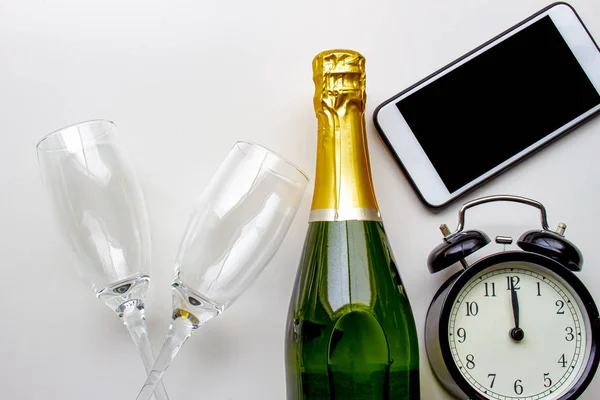 Neotevřená láhev šampaňského s prázdnými poháry, hodinami a chytrým telefonem na bílém pozadí — Stock fotografie