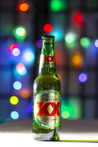 Láhev zelené láhve je pivo. Mexické pivo na bílém povrchu textury na barevných rozostřených světlech — Stock fotografie