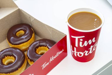 A box Tim Hortons Chocolate Dip Donuts with a coffee cup