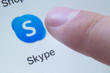 Calgary, Alberta, Kanada. 12 Mart 2020. Telekomünikasyon uygulaması olan Skype 'ı kullanmak üzere olan bir kişi beyaz ekranda bilgisayar, tablet, mobil cihazlar arasında görüntülü konuşma ve sesli arama sağlamakta uzmanlaşmıştır..