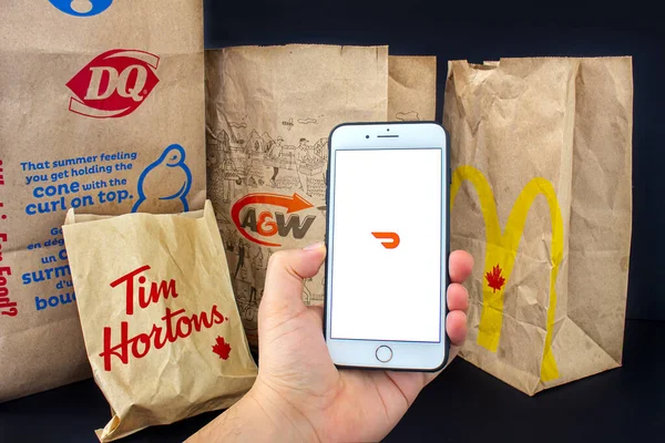 Calgary, Alberta. Kanada mı? 24 Nisan 2020: Tim Hourtons, A & W, McDonals ve DQ 'dan besin torbaları dağıtılmış halde iPhone Plus' ı elinde tutan kişi