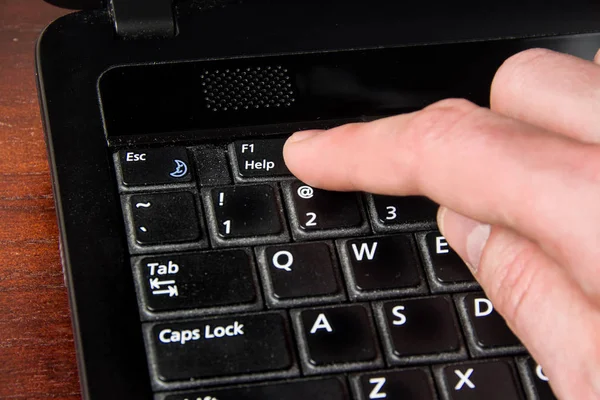 finger presses the Help key, laptop and hand