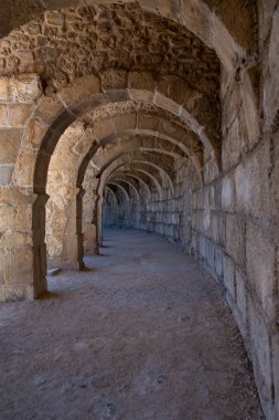 Türkiye 'nin Antalya kentindeki Roma Amfiteatrı Aspendos' un kemerli koridorlarından birinin güzel perspektifi. Önplanda ışık efekti olan güzel, dokulu duvarlar..