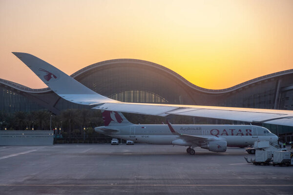 DOHA, QATAR - FEBRUARY 2020: Aircrafts of the Qatar airways fleet at Doha International Airport . Qatar Airways is rated as a 5-star airline. Hamad International Airport at sunset.