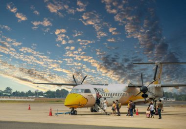 Ubon Ratchathani / Tayland - Şubat 2020: Nok Air Airlines 'ın pervaneli uçağı kalkış sırasında Ubon Ratchathani Havaalanı' na park ediyor. Yolcular uçağa binmek için yürüyorlar.