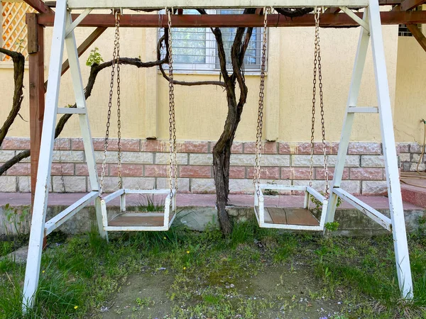 Two metal white swings in the house\'s garden