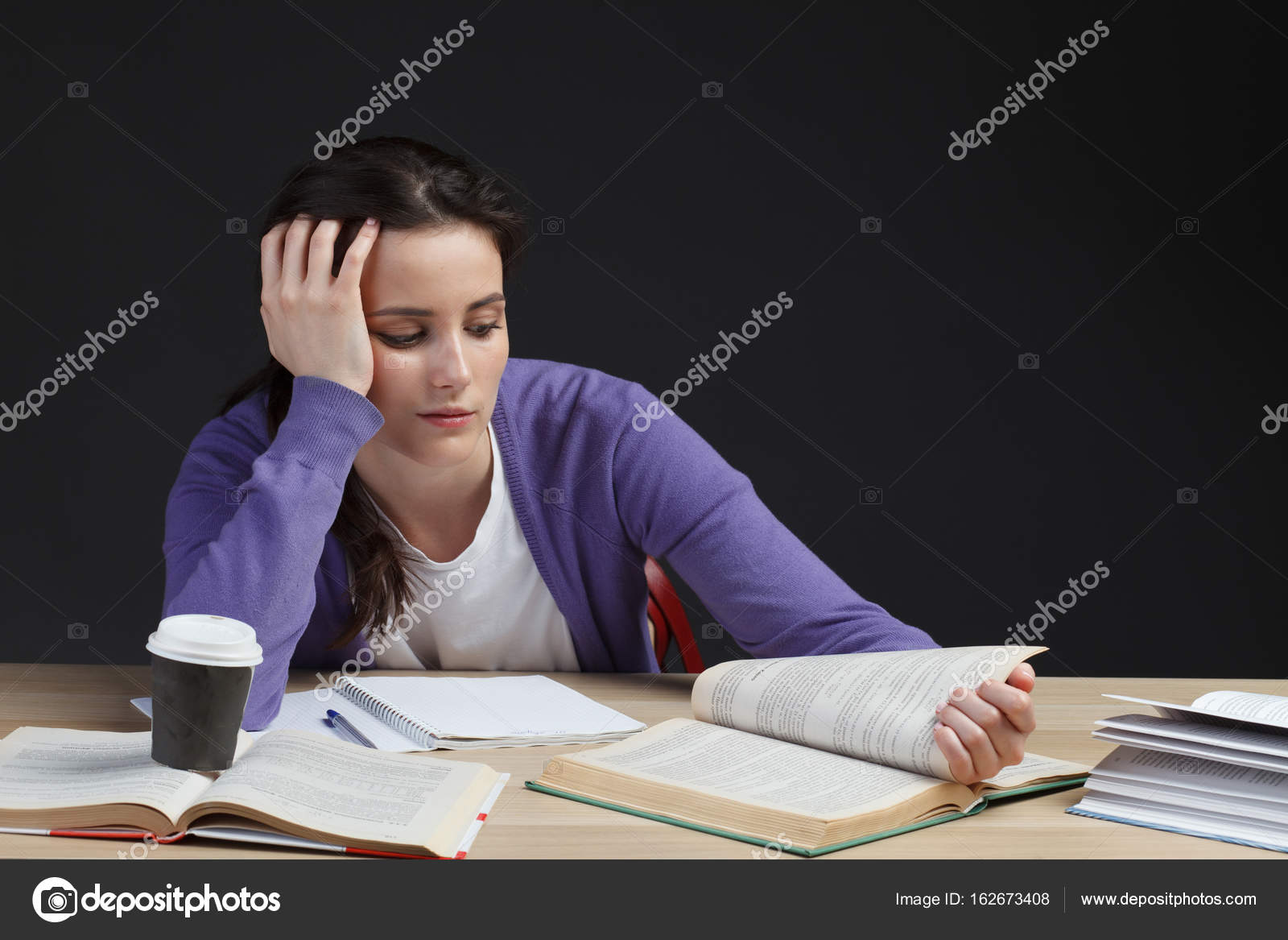 Female Student Boring With Book In Classroom Desk Stock Photo