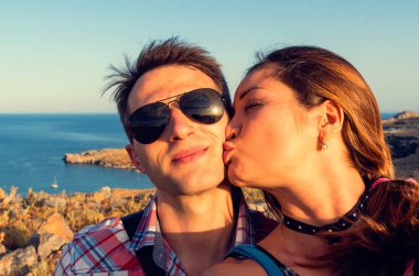 Rhodes 'ta mutlu bir çift. O mutlu bir şekilde gülümserken, kız adamı yanağından öpüyor..