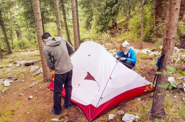Men setting a tent in the wild. Escape to the forest.