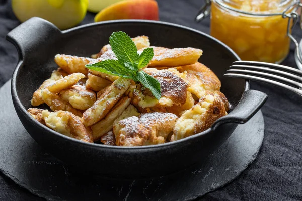 Kaiserschmarrn with apple sauce, mint leafes in a black pan — Stock Photo, Image