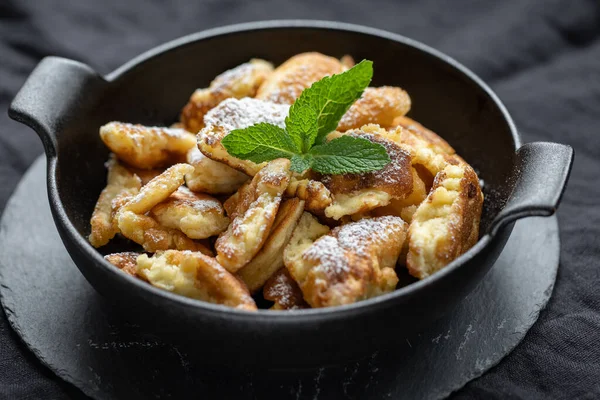 Kaiserschmarrn in a black pan with mint leaf