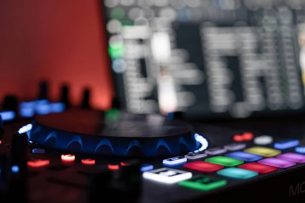 Bulanık arkaplanda DJ dizüstü bilgisayarı olan bir DJ denetleyicisinin yan görünümü